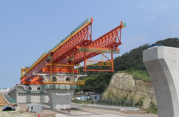 Launching gantry positioned at a pier, with the main truss and lifting equipment carried above deck level.