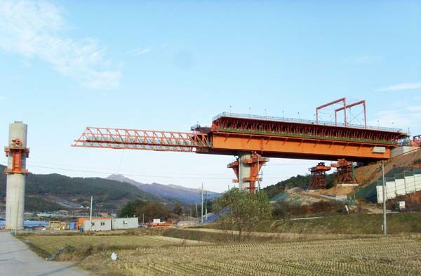 Movable scaffolding system with its forward nose extended beyond the pier towards the next span, the formwork and working platforms in place behind it.