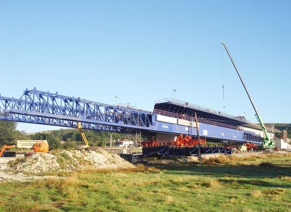 Overhead movable scaffolding system viewed along the deck, showing the main truss, the suspension frames and the formwork carriage below.
