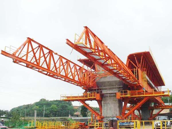 Underslung movable scaffolding system at a pier, its main truss girders carried at deck level on legs and brackets seated on the pier, with the formwork carried by the girders.